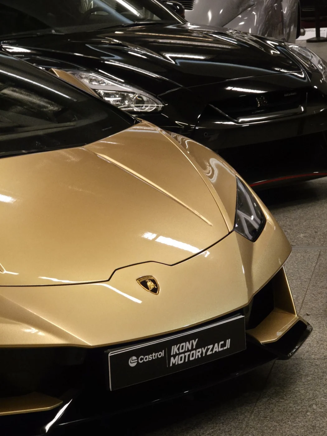 Złote Lamborghini i czarny sportowy samochód w tle